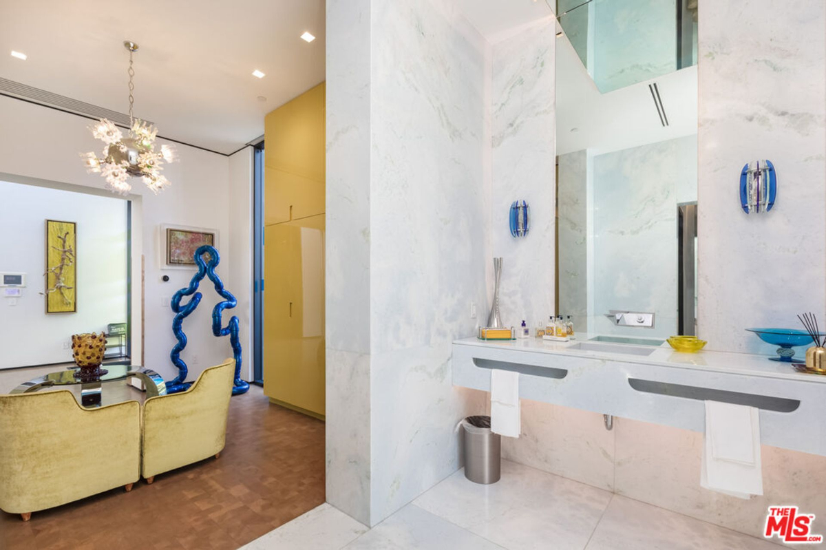 Bathroom with marble finishes and a minimalist design. A sitting area is visible in the background.