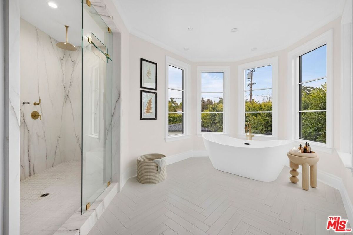 Bathroom with a large soaking tub, a walk-in shower, and multiple windows providing natural light. The floor and walls are light-colored.