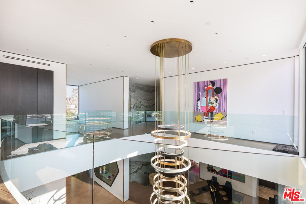 Modern home interior with a double-height ceiling, glass railings, and a unique light fixture.