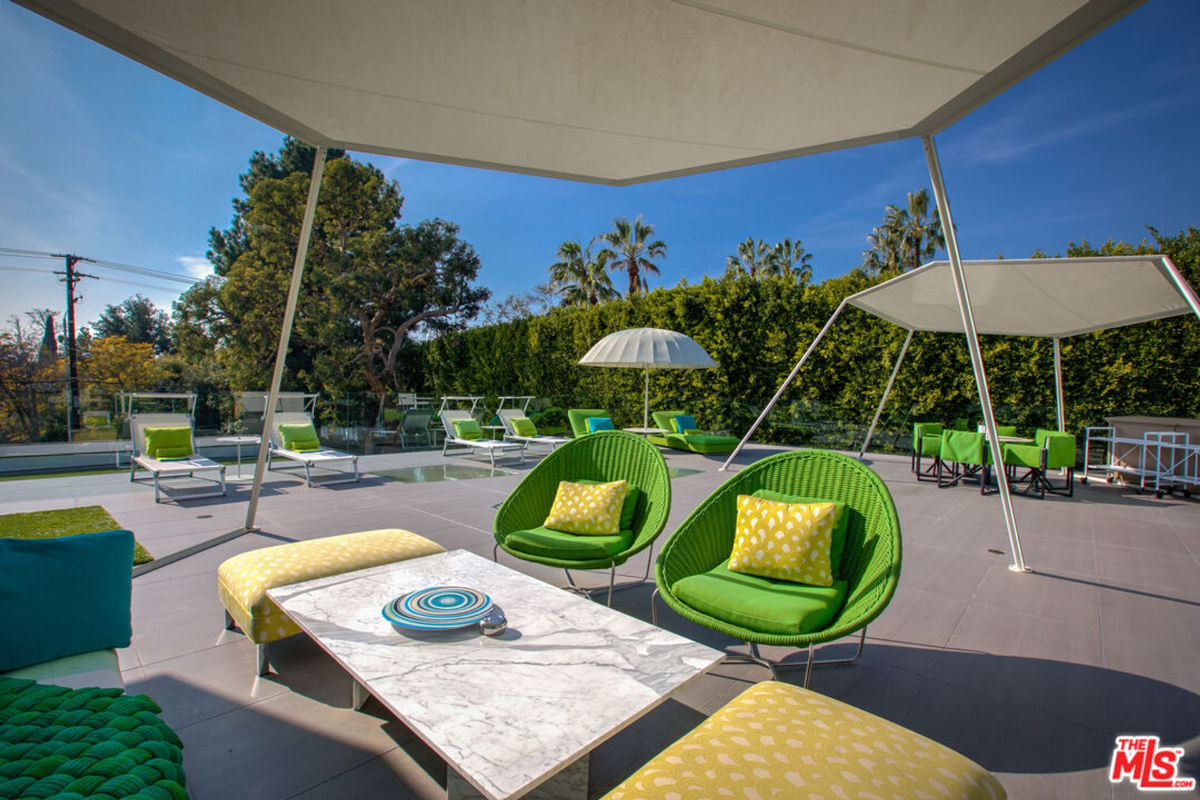 Outdoor patio or deck area with lounge chairs, a dining table, and a modern canopy.