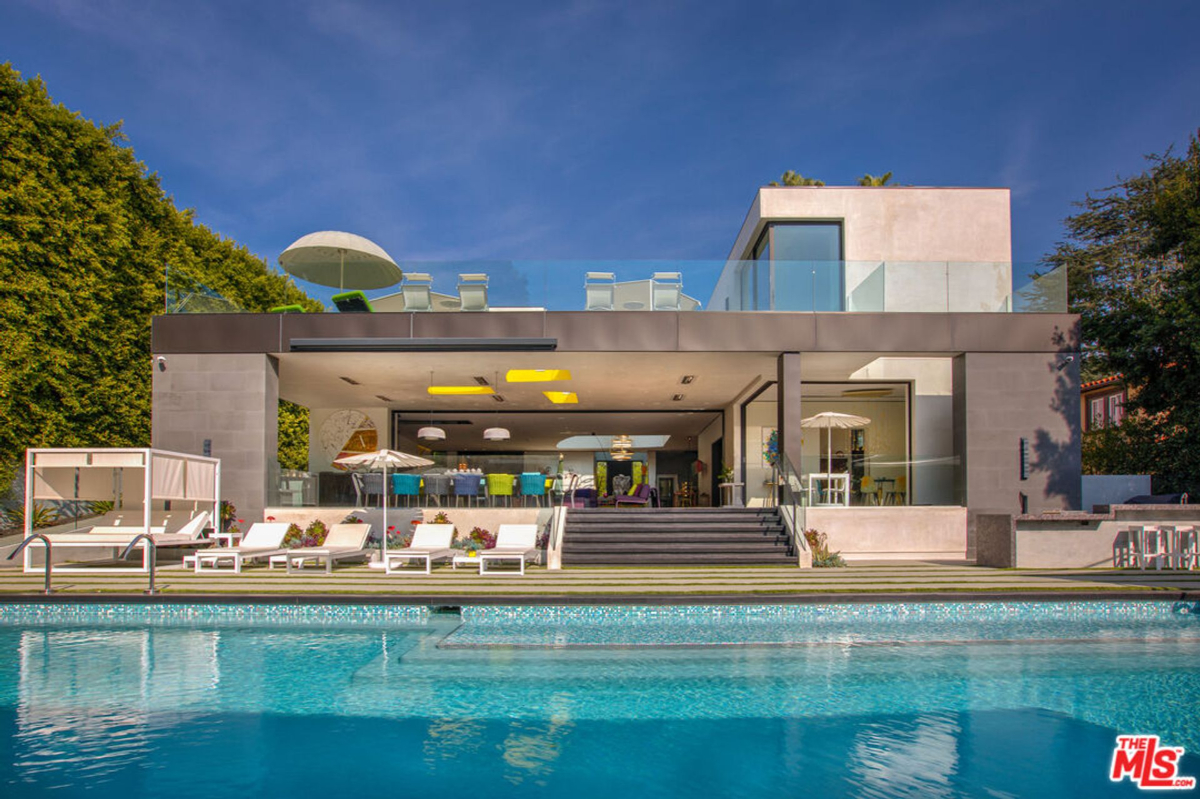 Modern house with a large swimming pool and expansive patio area.