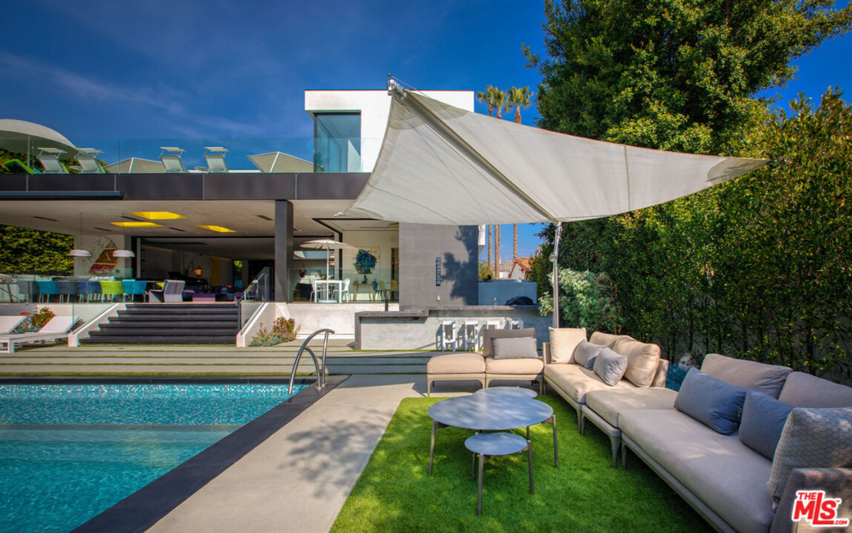 A modern home with a swimming pool and a shaded seating area.