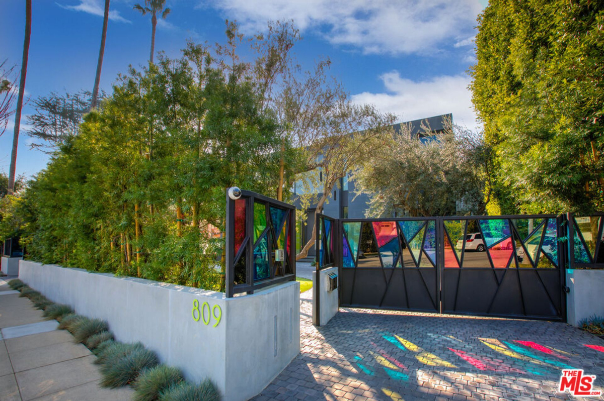 Colorful glass accents a modern gate, adding a playful touch to a secluded property.