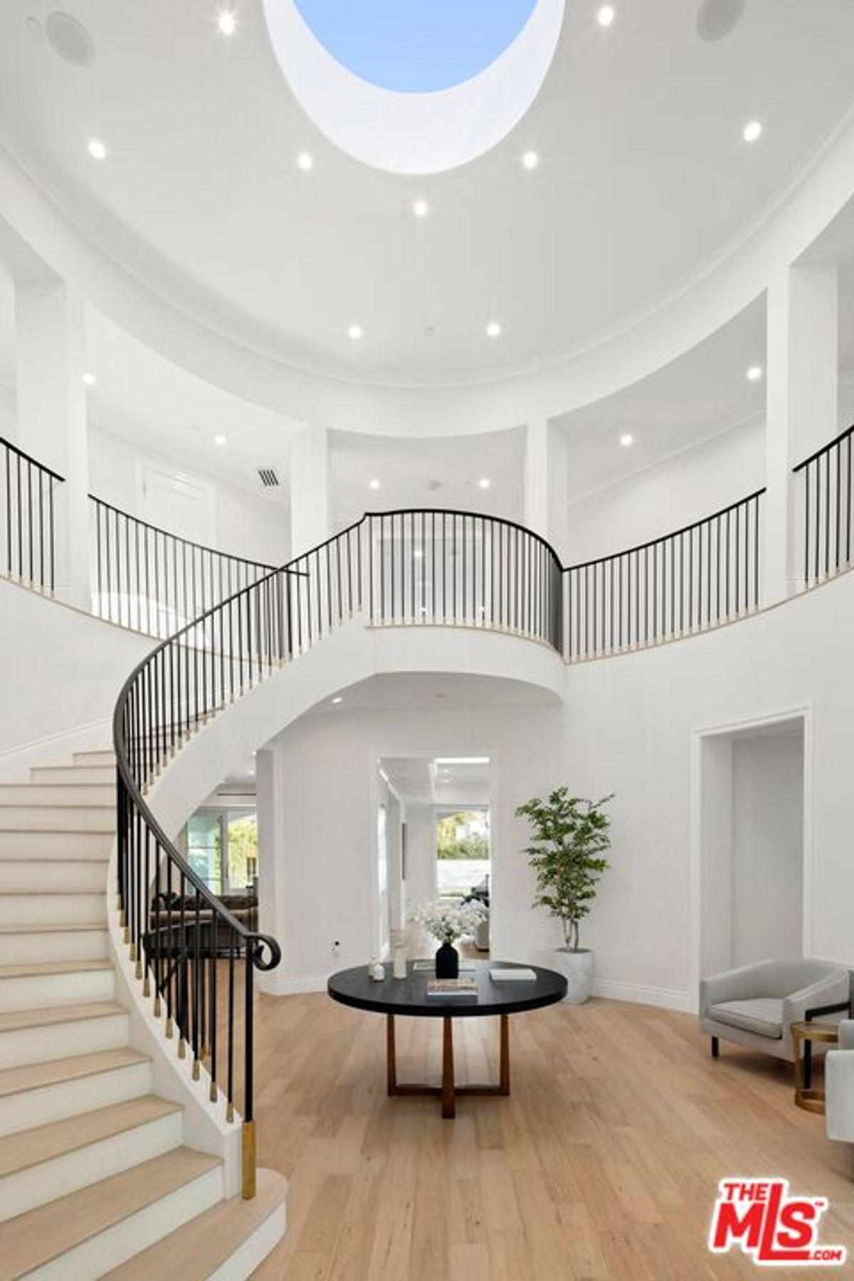 Elegant, curved staircase dominates a bright, two-story foyer with a circular skylight.