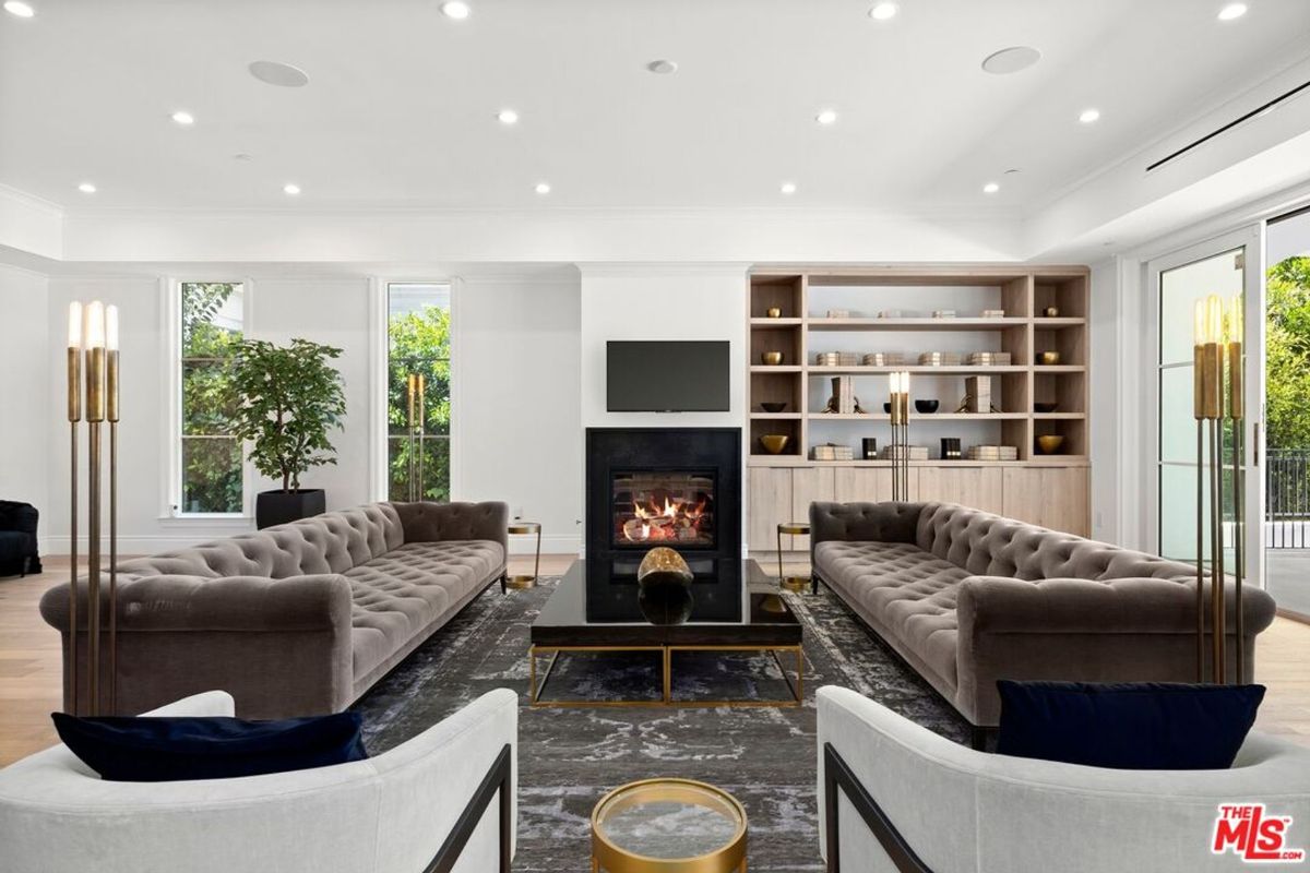 Modern living room boasts two long, tufted sofas flanking a fireplace and built-in shelving.