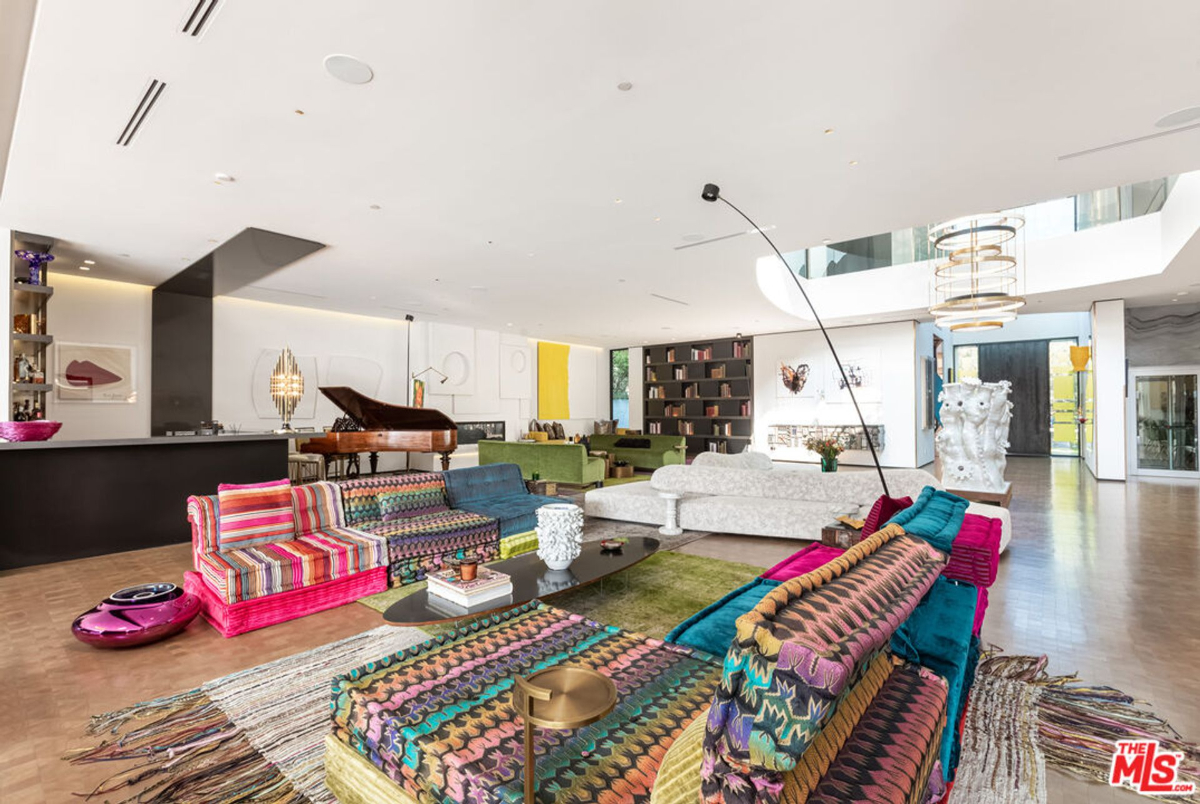 A grand living area features a double-height ceiling and vibrant, eclectic furnishings.