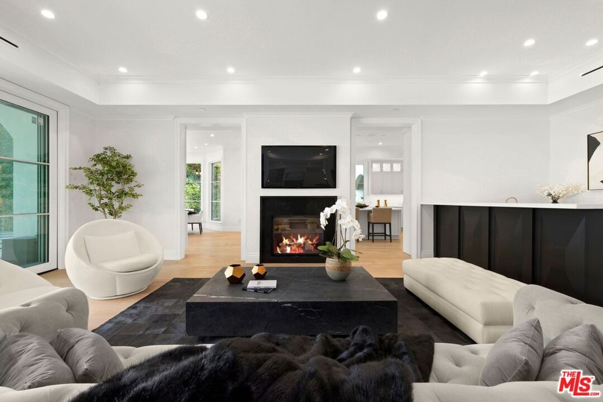 Modern living room features a large, dark gray coffee table, white sofas, and a fireplace as a focal point.