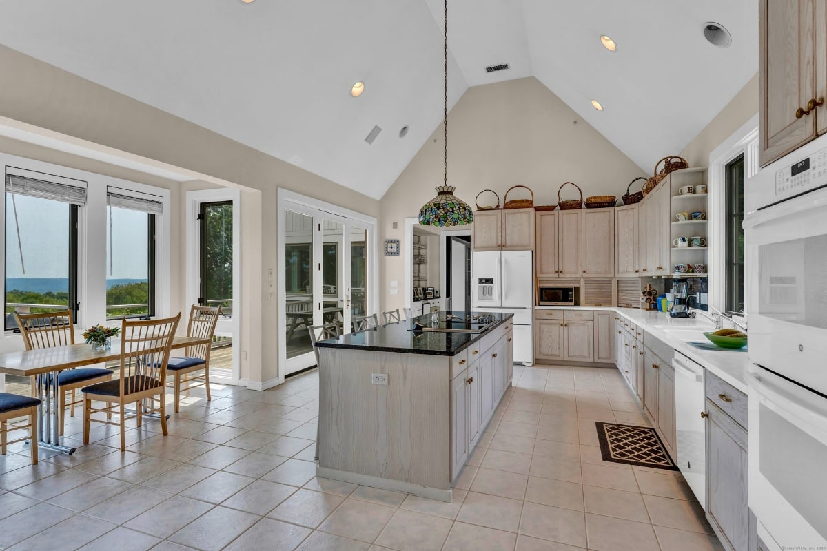 Large island with a dark countertop, ample cabinetry, and a dining area with large windows offering an outdoor view.