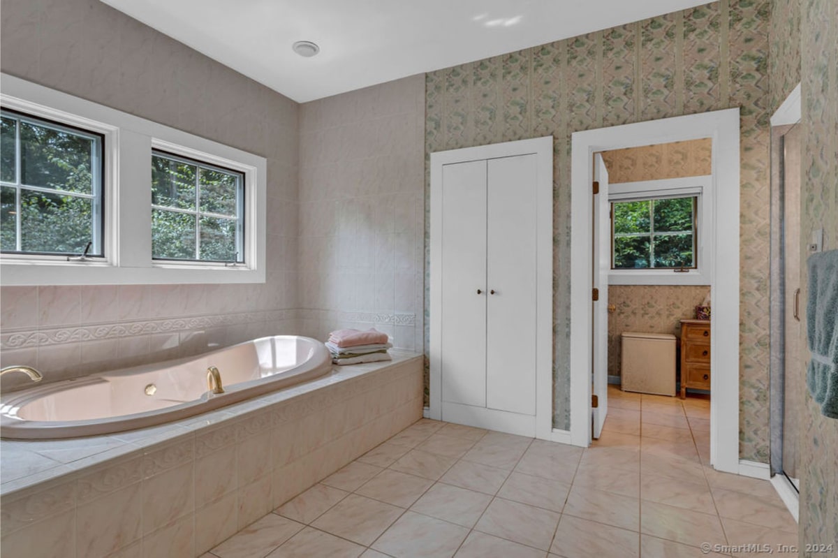 This spa-like bathroom features a large, free-standing soaking tub and two windows providing natural light. 