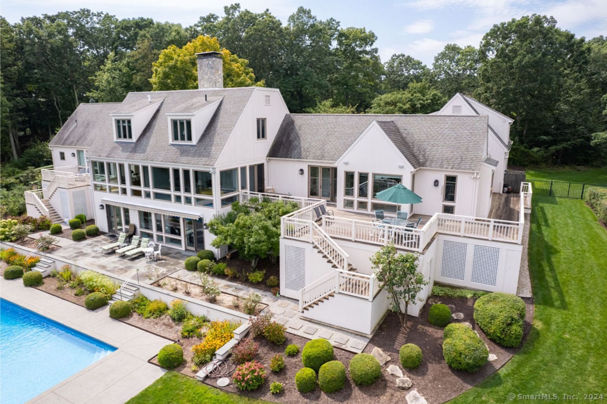 Mansion with multiple decks, a pool, and lush landscaping.