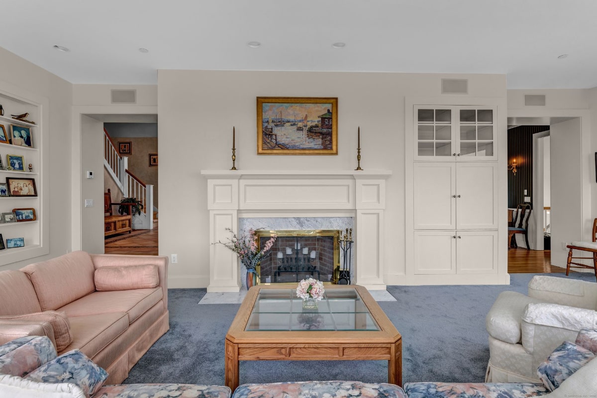 Bright living room features a fireplace, light pink sofas, and built-in cabinetry.