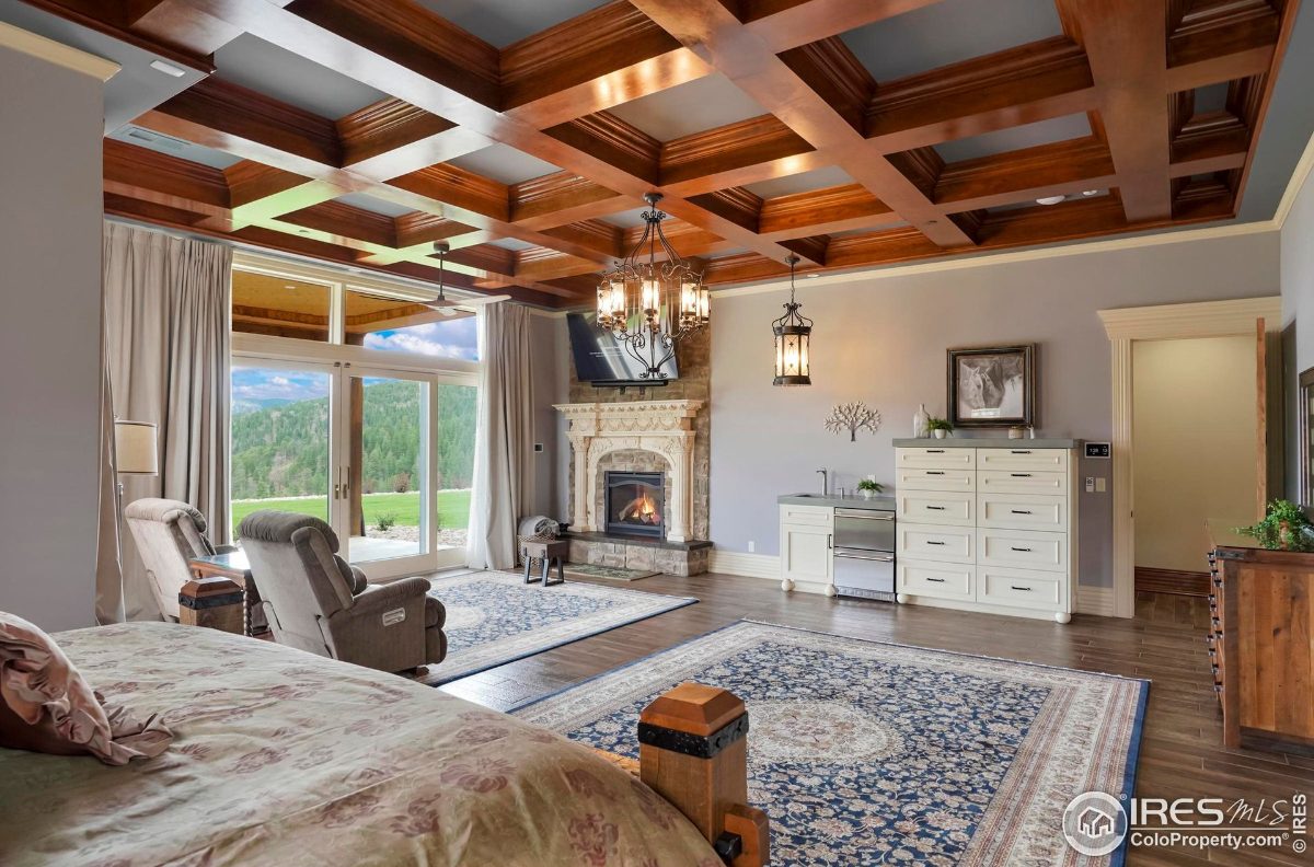 Relaxing master suite boasts a fireplace, coffered ceiling, and access to outdoor views.