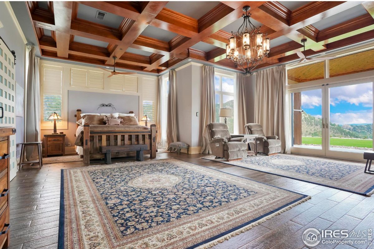 Elegant master bedroom features a wood-beamed ceiling, large windows, and a plush area rug.