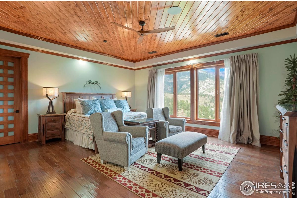 Serene guest bedroom offers a wooden bed, calming blue walls, and scenic outdoor access.