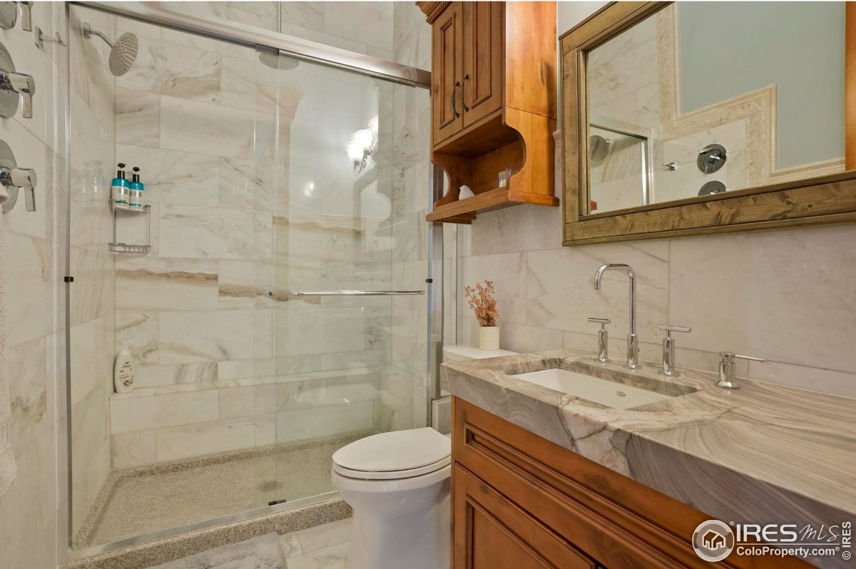 Clean and modern bathroom features a walk-in shower, vanity with marble countertop, and a toilet.