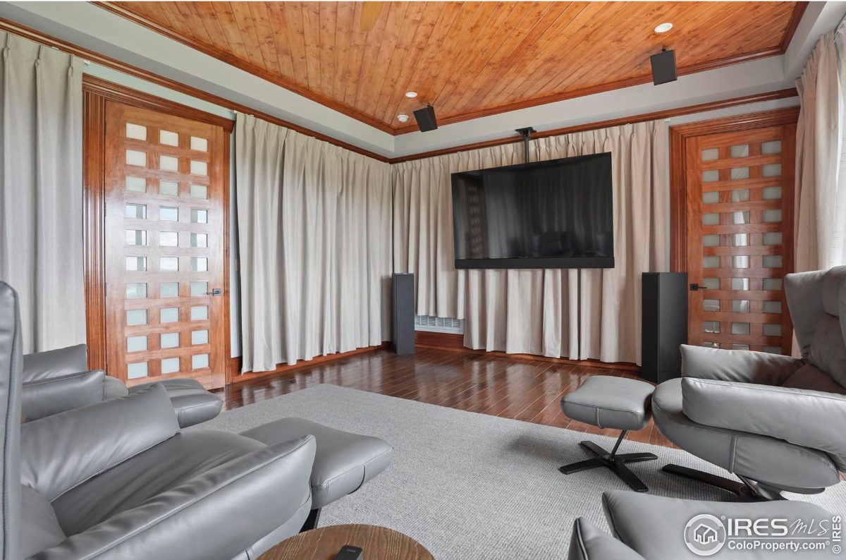 Home theater room features a large screen TV, comfortable seating, and wood-paneled walls and ceiling.