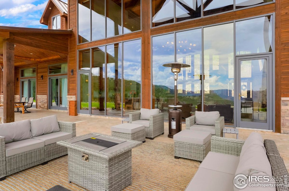 Covered patio area features comfortable wicker furniture, a fire pit, and expansive views of the surrounding landscape.