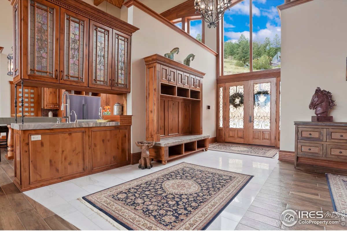 Elegant entryway features stained-glass cabinets, a built-in bench, and large windows offering scenic views.