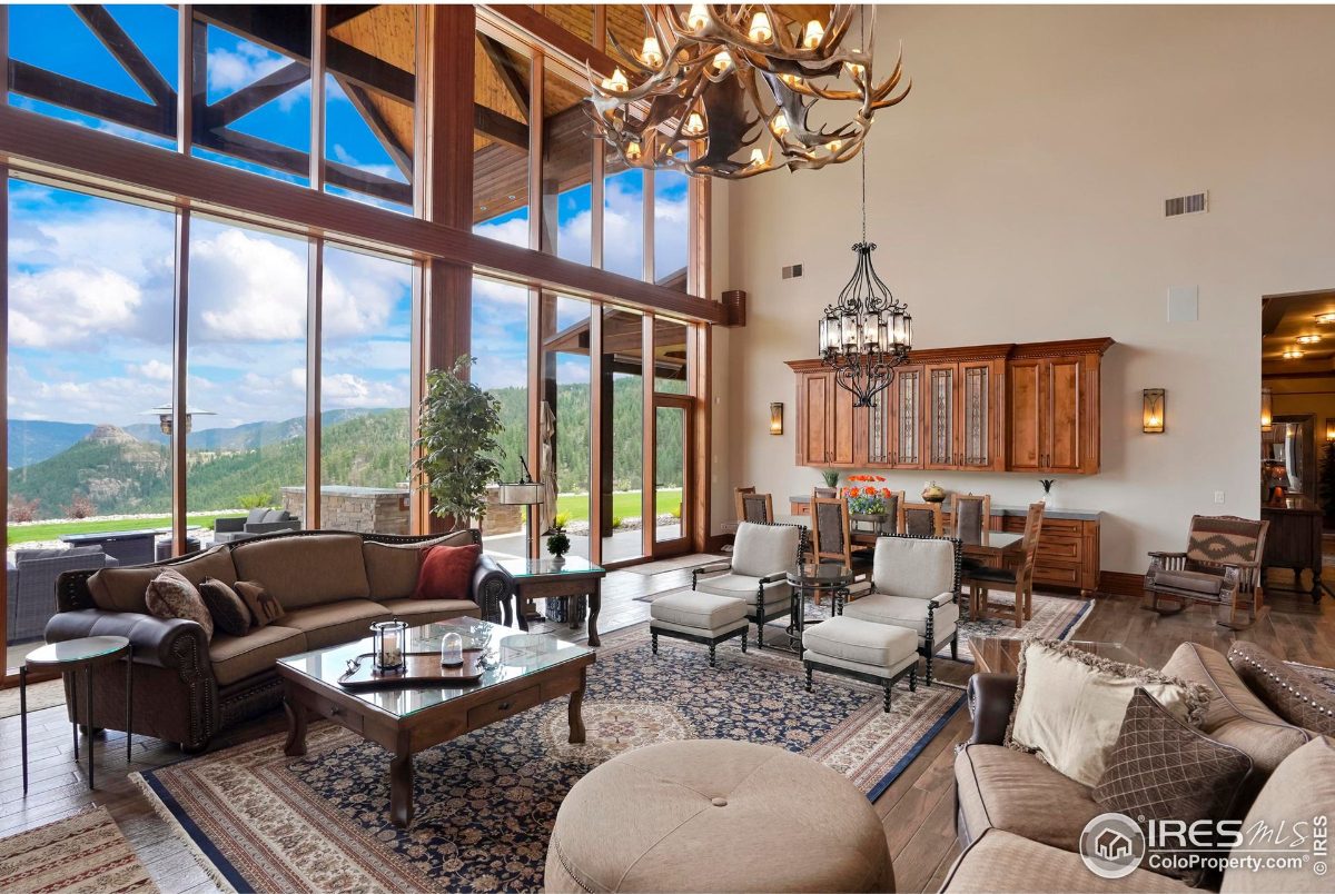 Open-concept living area features floor-to-ceiling windows showcasing stunning mountain views, complemented by comfortable seating and a dining area.