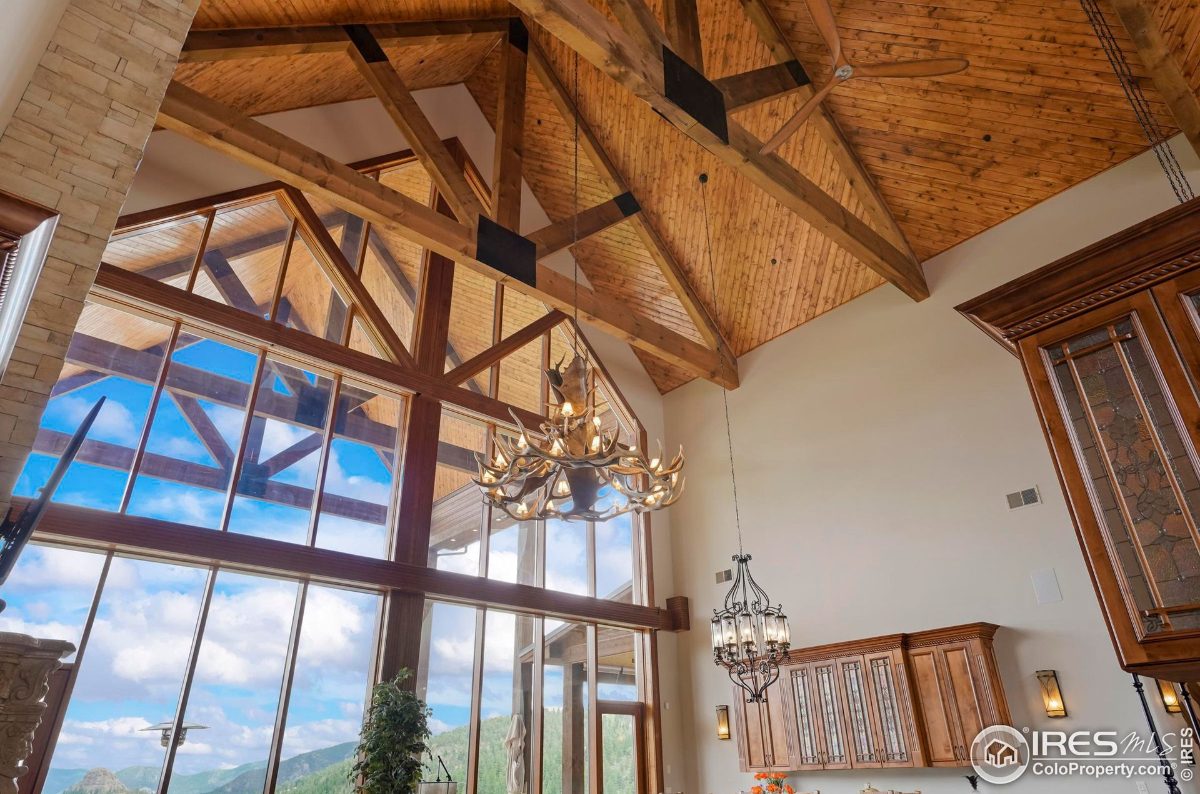 High-ceilinged great room showcases a dramatic antler chandelier and expansive windows, creating an airy and open atmosphere.