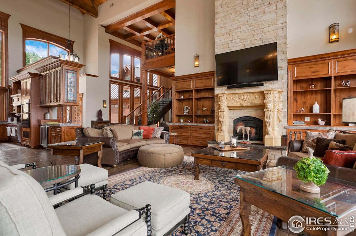 Spacious great room features a large stone fireplace, built-in shelving, and a comfortable seating arrangement, creating a warm and inviting ambiance.