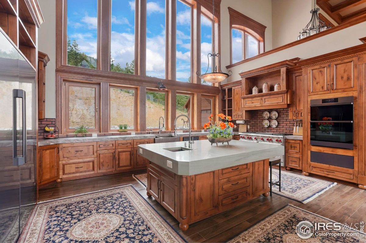 Bright kitchen features a large island, custom cabinetry, and expansive windows offering natural light and scenic views.