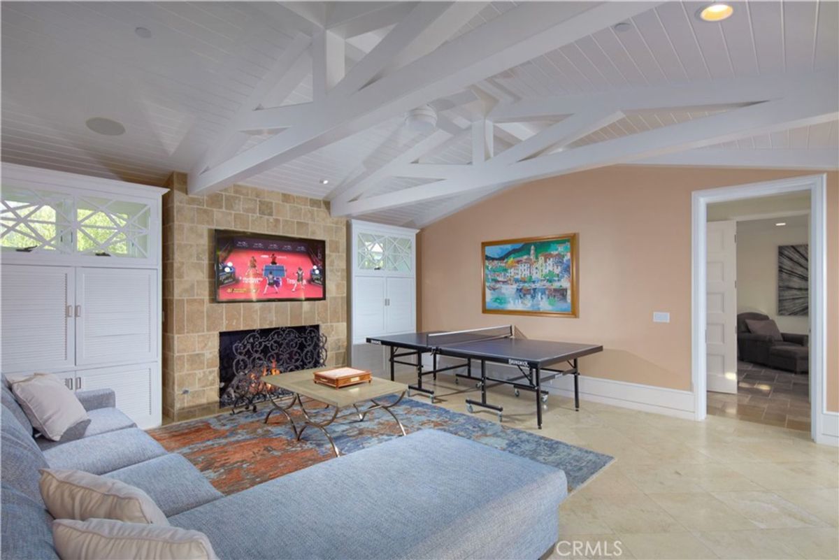 A game room features a fireplace, comfortable seating, and a ping pong table.