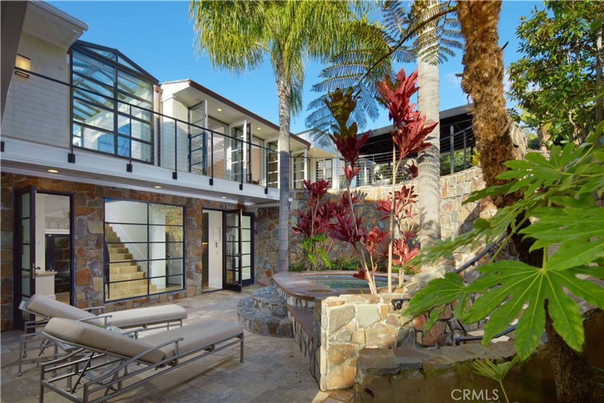 Lush landscaping complements a stone and glass home's secluded patio.