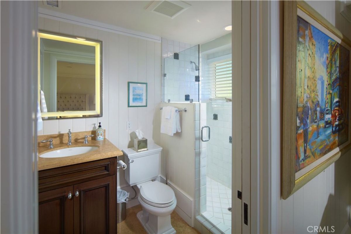 Bathroom with a shower, toilet, and sink. The walls are paneled.