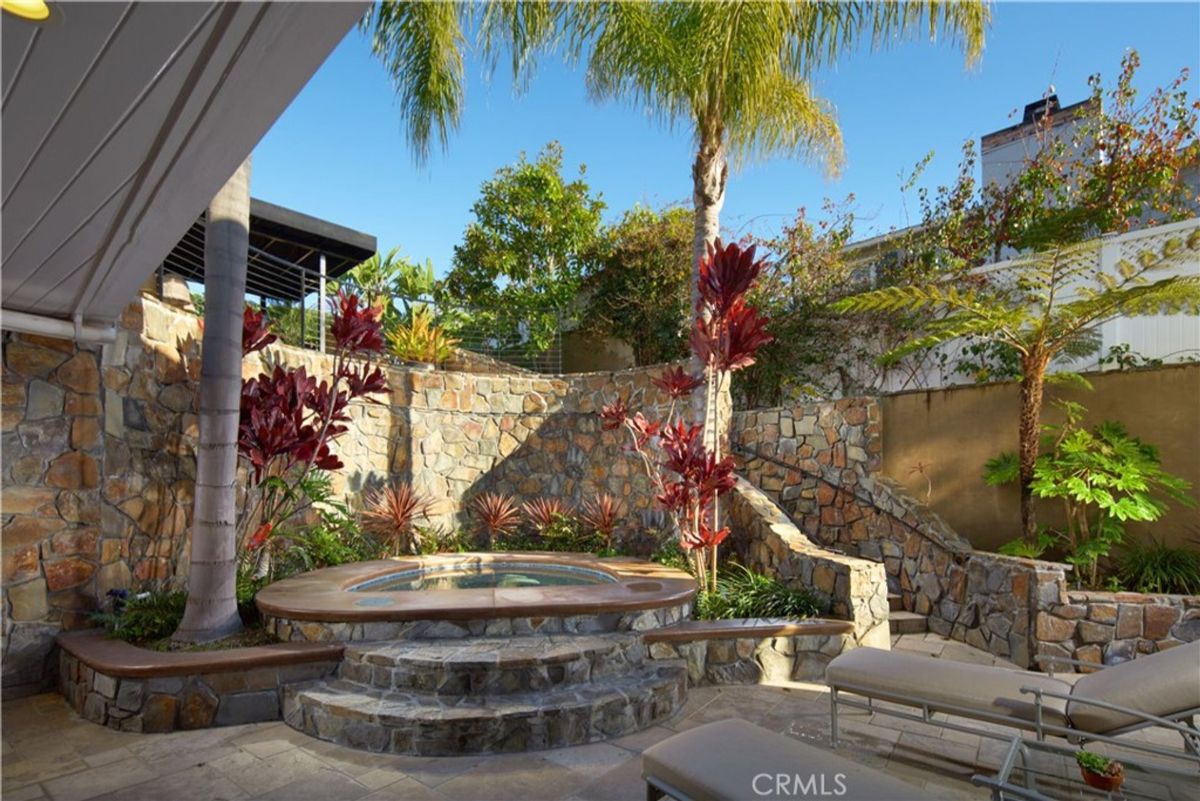 Stonework surrounds a tranquil spa nestled in a garden.