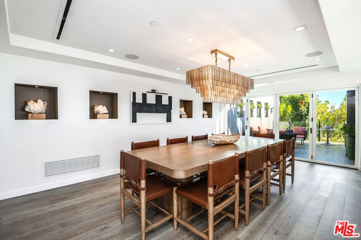 Elegant dining room features a large wooden table, leather chairs, and a statement chandelier.