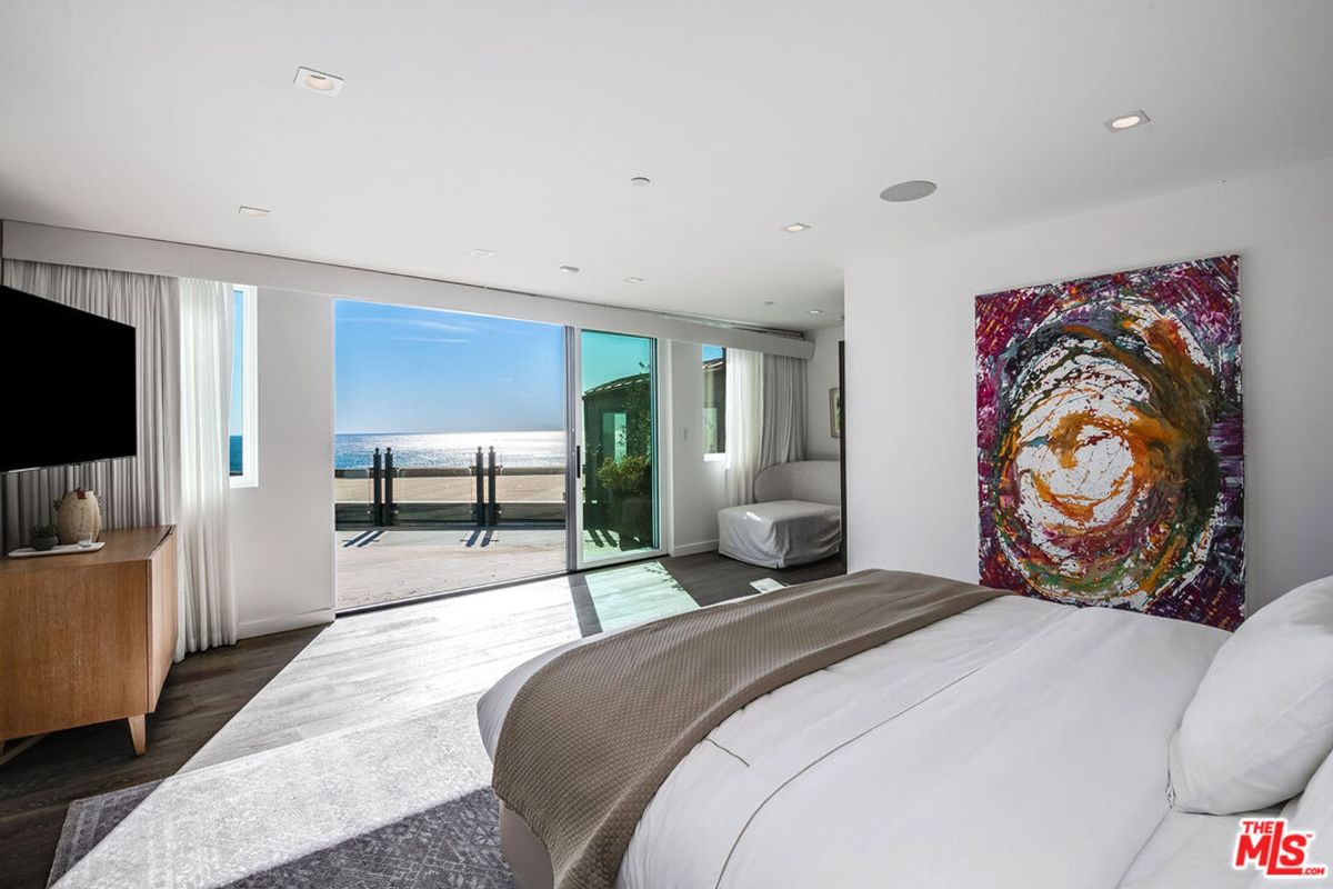 Ocean-view bedroom features floor-to-ceiling windows, a large bed, and modern decor.