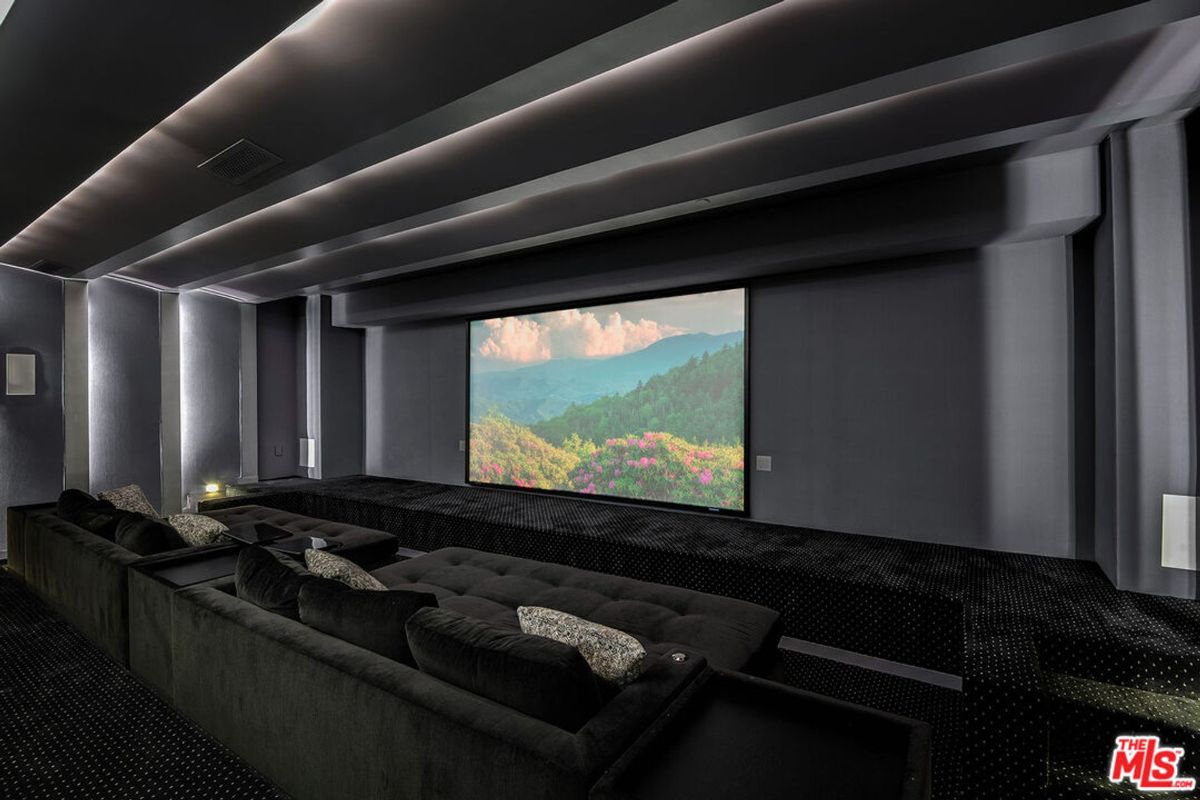 Home theater features a large projection screen, comfortable seating, and dark walls.