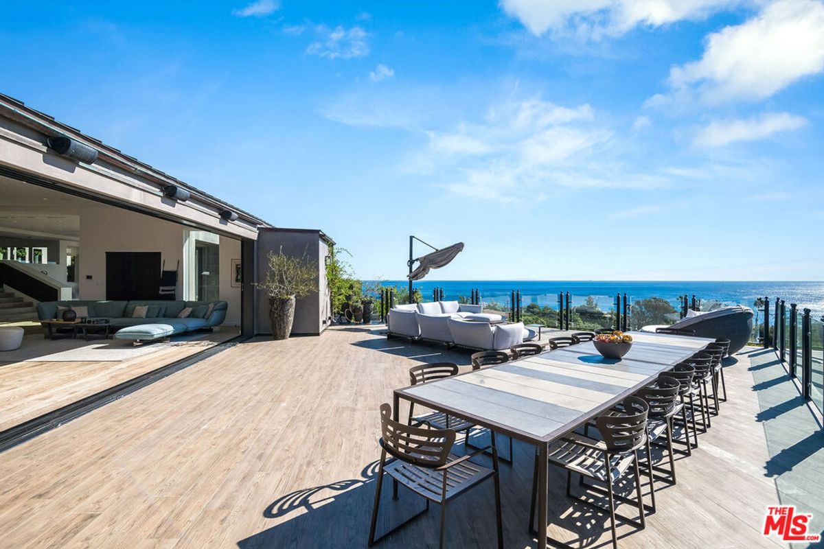 Expansive outdoor patio offers stunning ocean views, comfortable seating, and a large dining table.