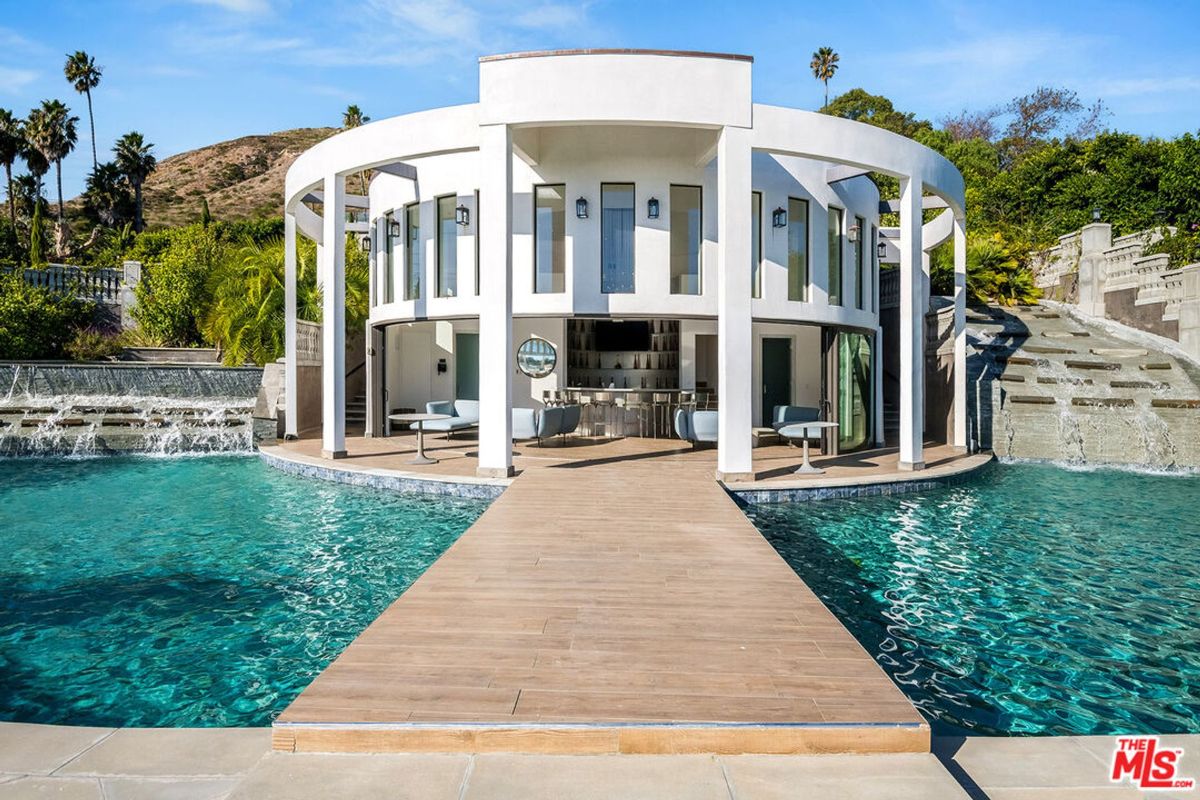 Circular poolside bar and lounge area with a walkway leading to it.