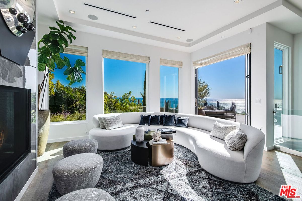 Ocean views grace the living room, featuring curved sofa and modern coffee table.