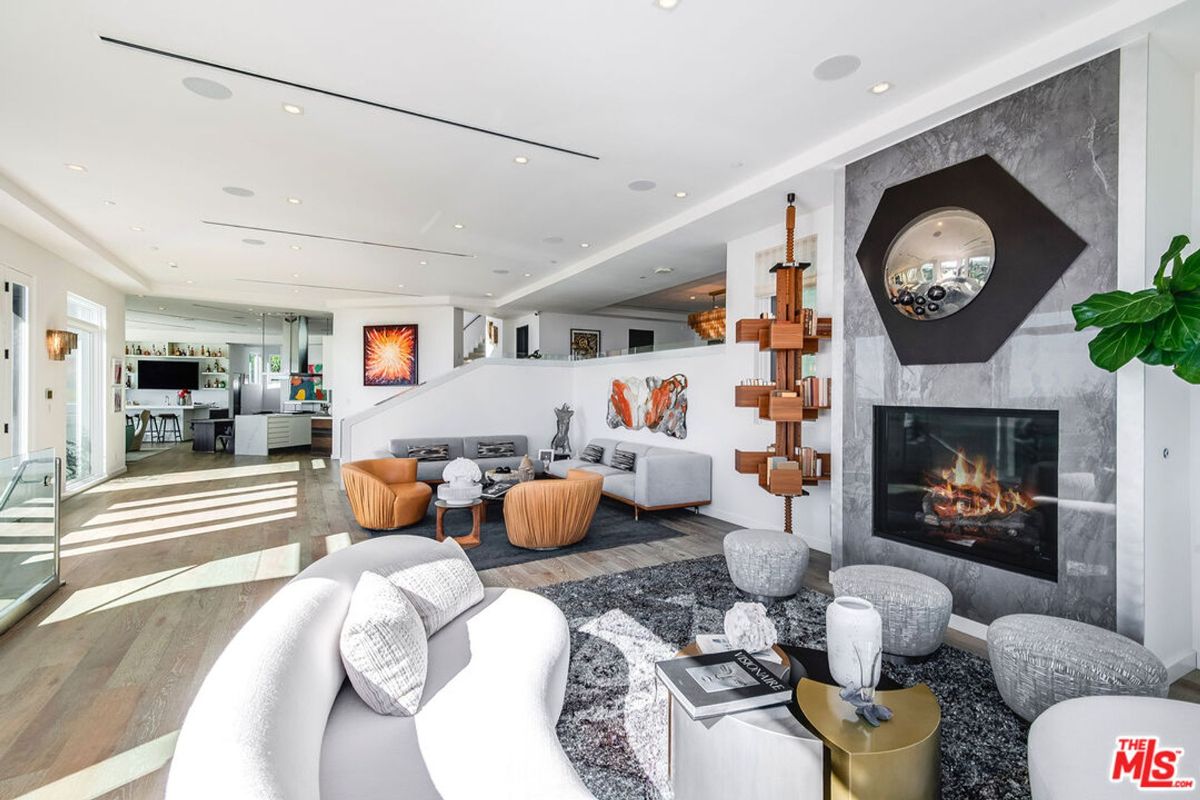 Open floor plan showcases modern furniture, fireplace, and striking artwork.