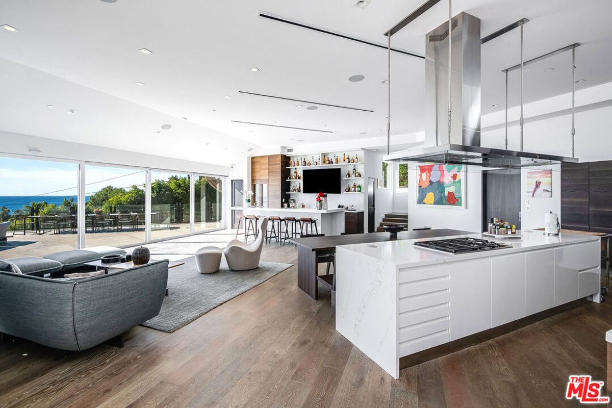 Modern kitchen and living area blend seamlessly, showcasing expansive windows and sleek design elements.