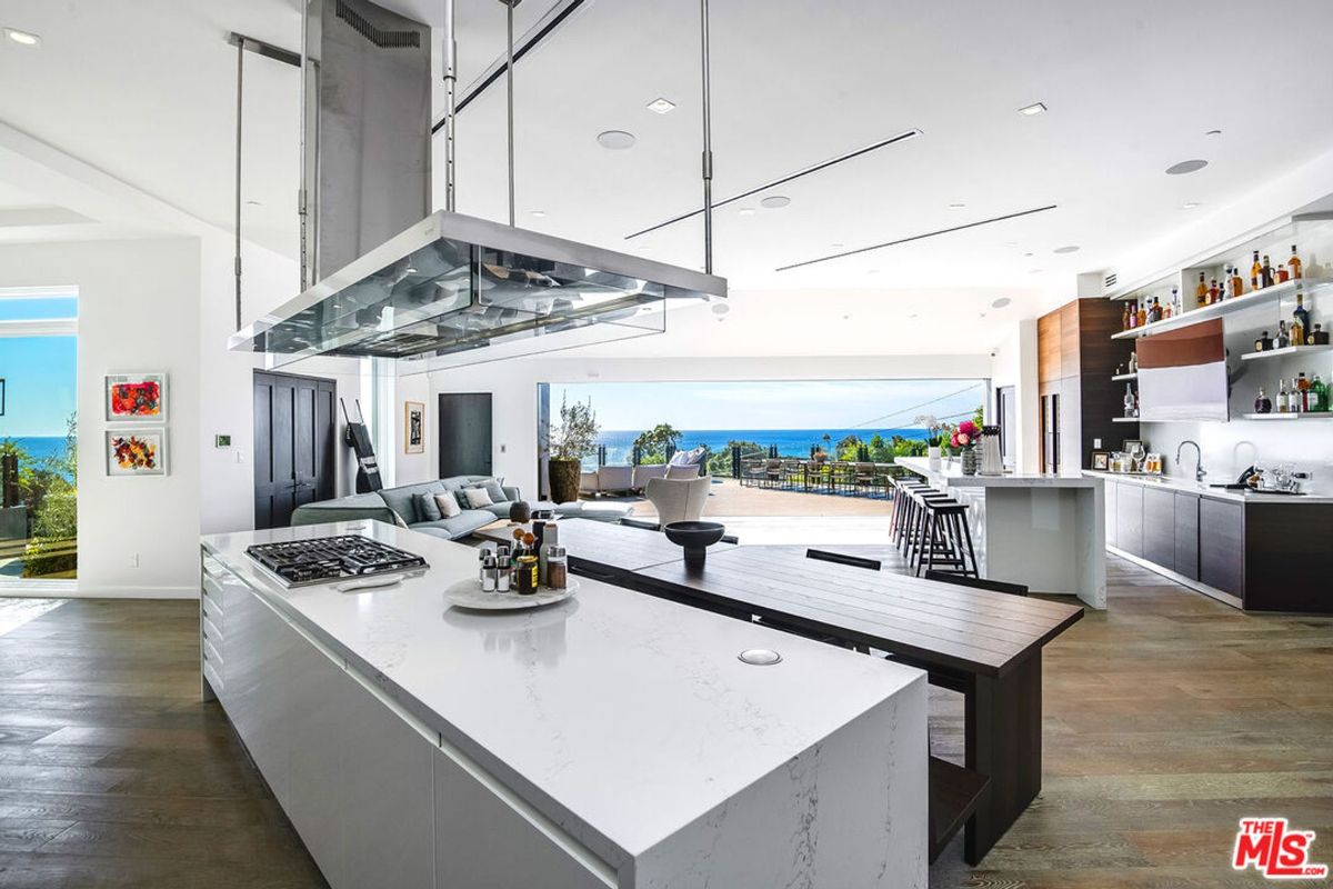 Modern kitchen features expansive island, high-end appliances, and stunning ocean views.