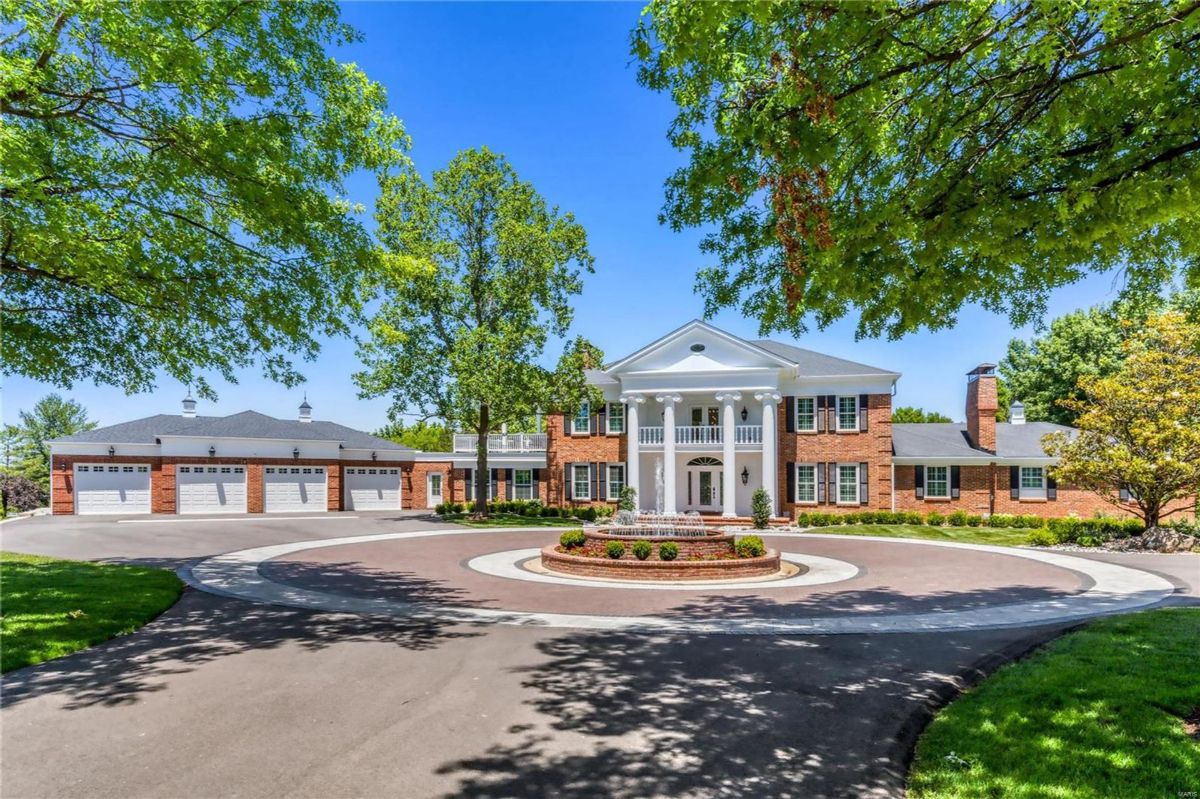 A large brick home with white columns and a circular driveway is shown.