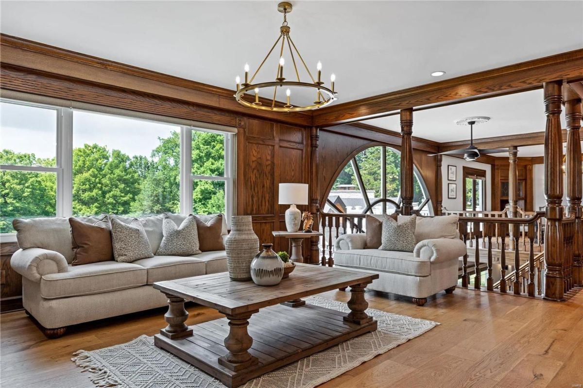 Hardwood floors and dark wood paneling create a warm atmosphere in this spacious living area. 