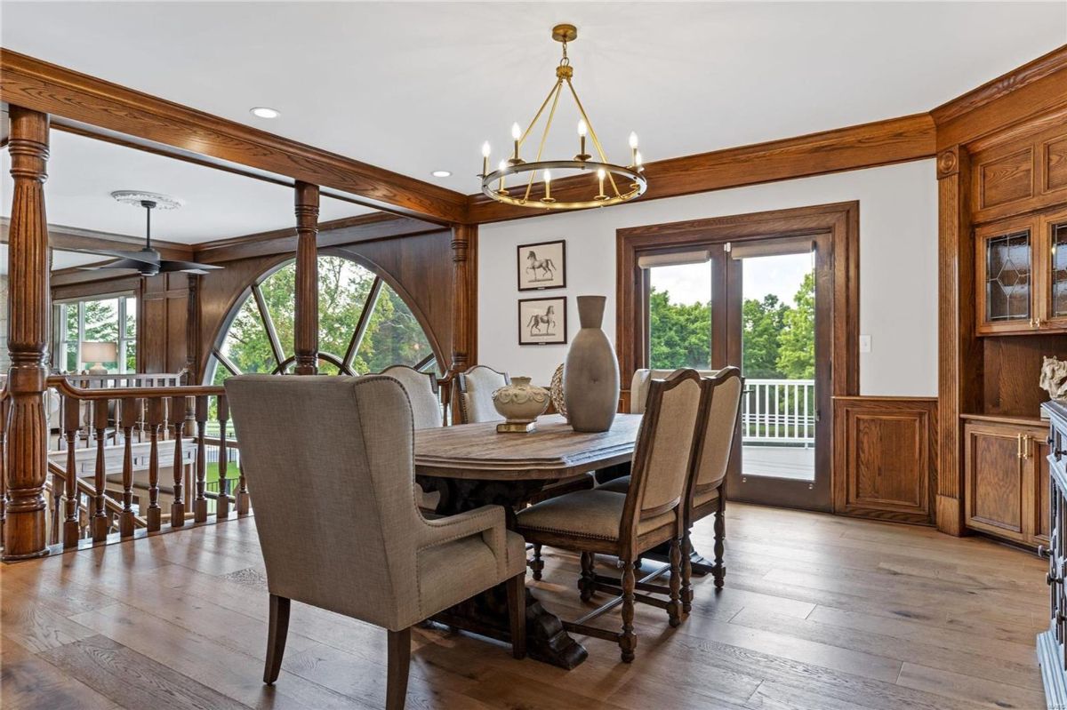 An elegant dining room features a large wooden table surrounded by upholstered chairs. 