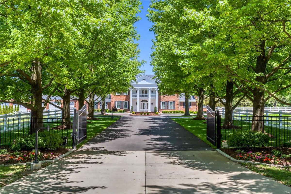 The property is gated, with a white fence visible along the sides of the driveway. 