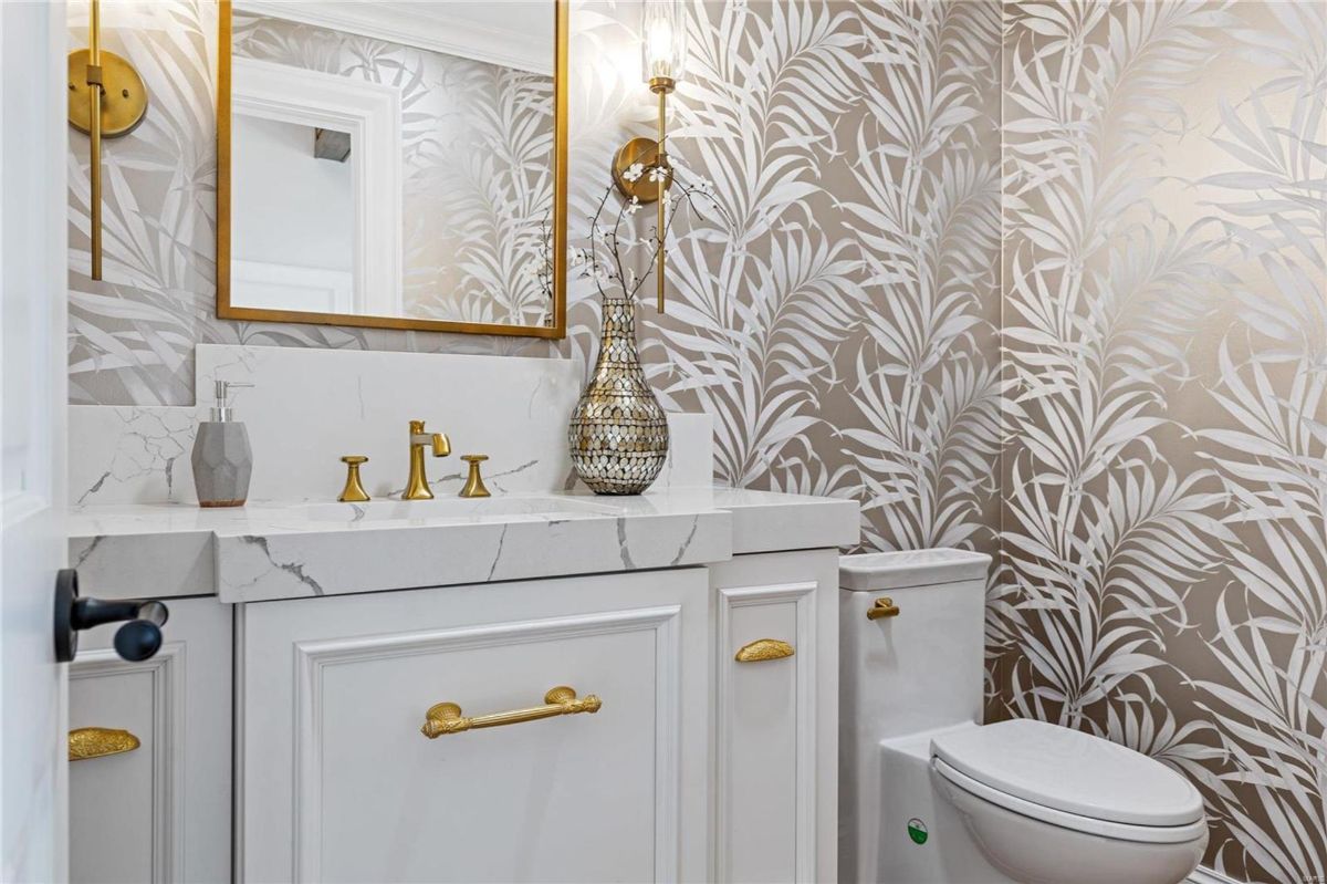 An elegant powder room features a white vanity with gold hardware and a marble countertop. 