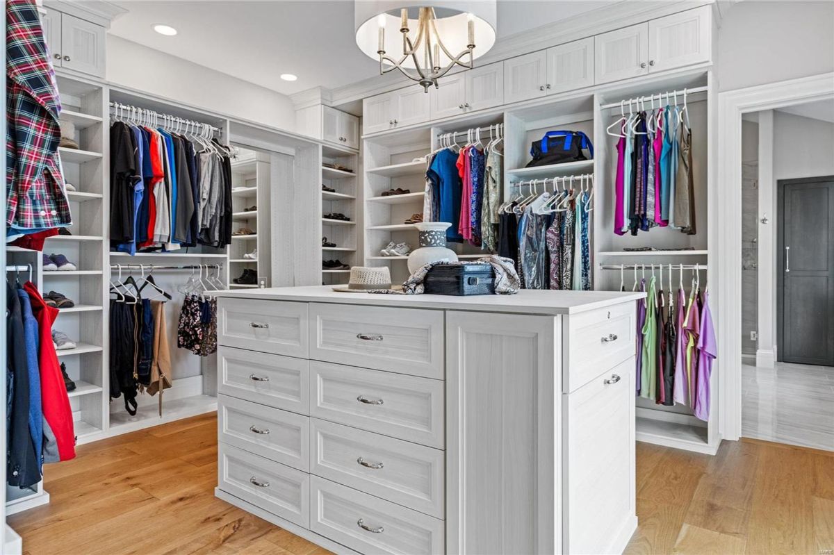 Large walk-in closet features extensive white shelving and hanging space for clothing.