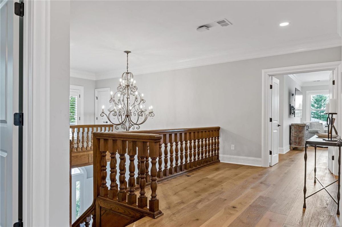 Hallway with hardwood floors and a wooden railing overlooks a lower level.