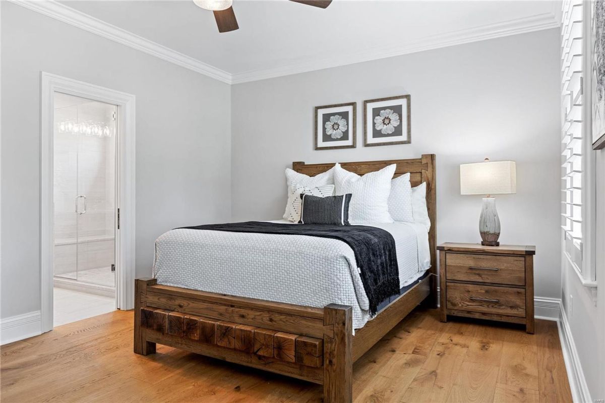 Bedroom with hardwood floors features a rustic wood bed frame and a white duvet cover. 