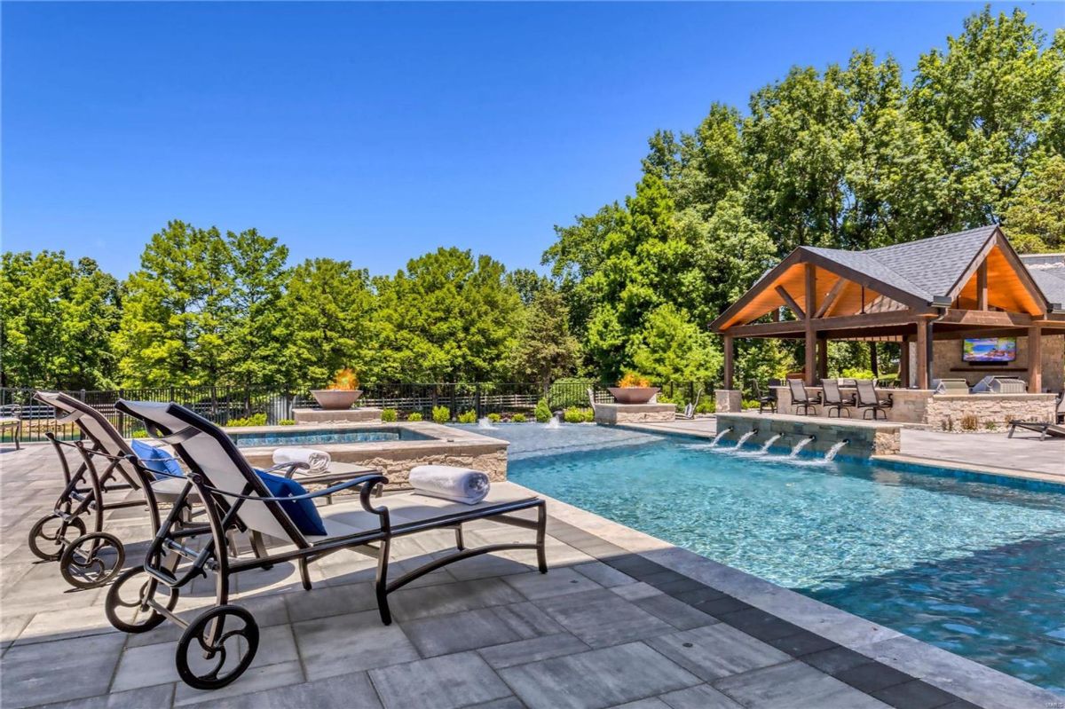 Resort-style backyard features a large swimming pool with multiple water features, a spa, and lounge chairs