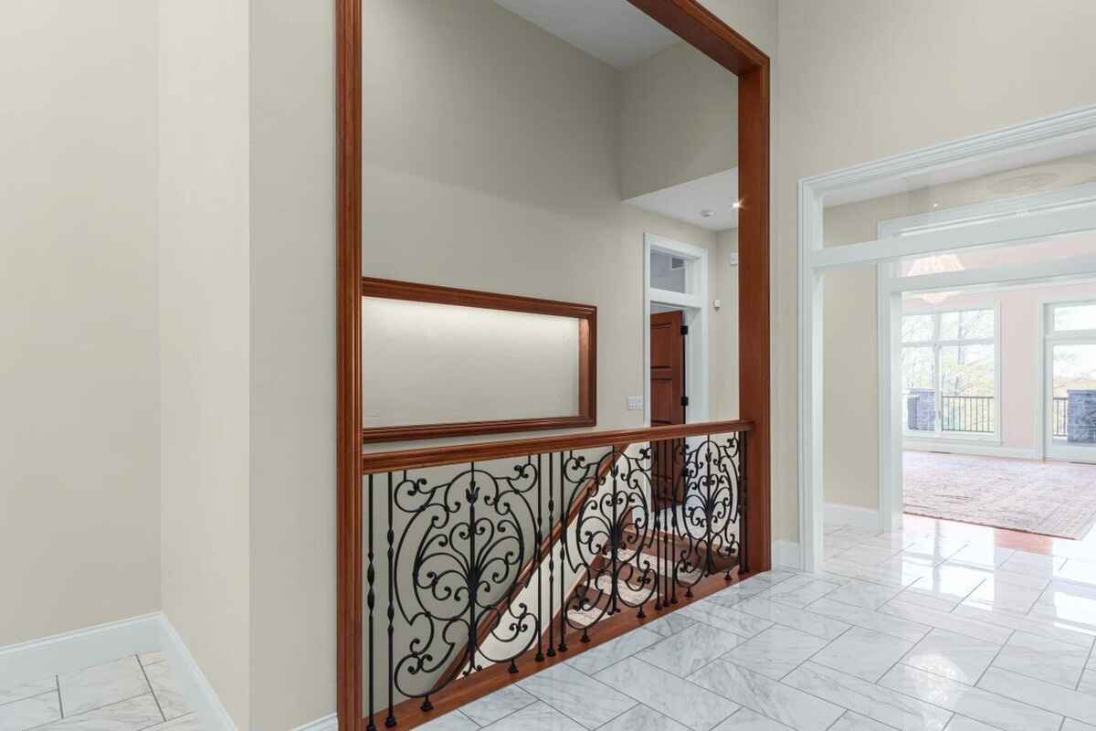 Hallway features a decorative iron railing, marble flooring, and open access to adjacent rooms.