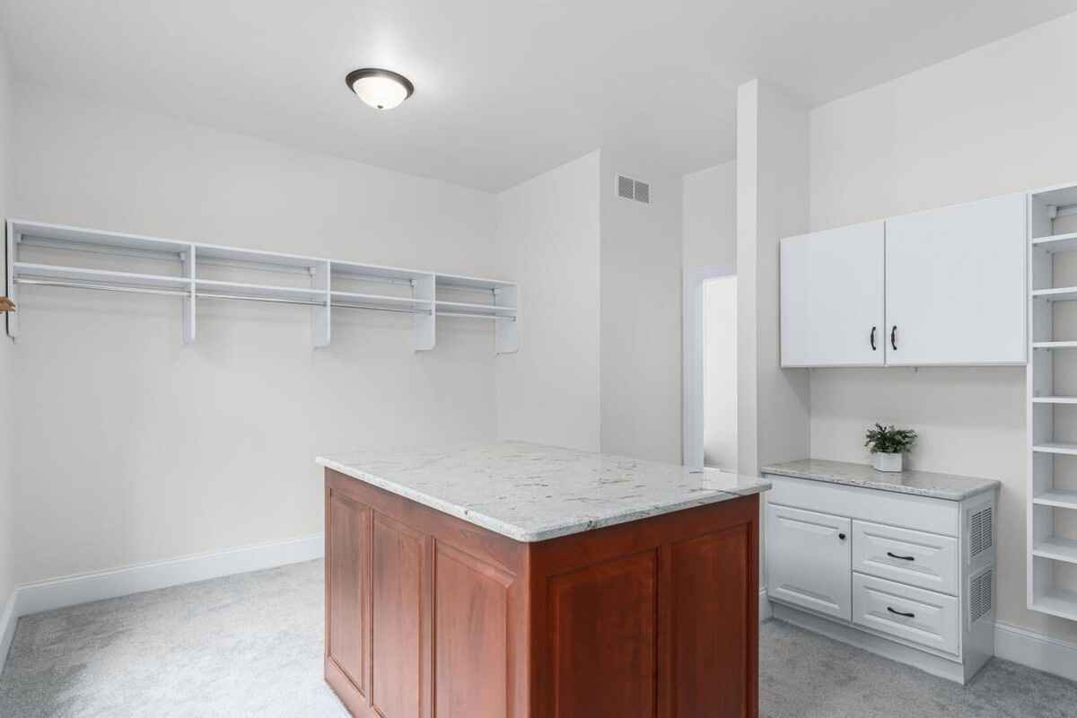 Walk-in closet features a marble-topped island, shelving, and additional built-in cabinetry for storage.